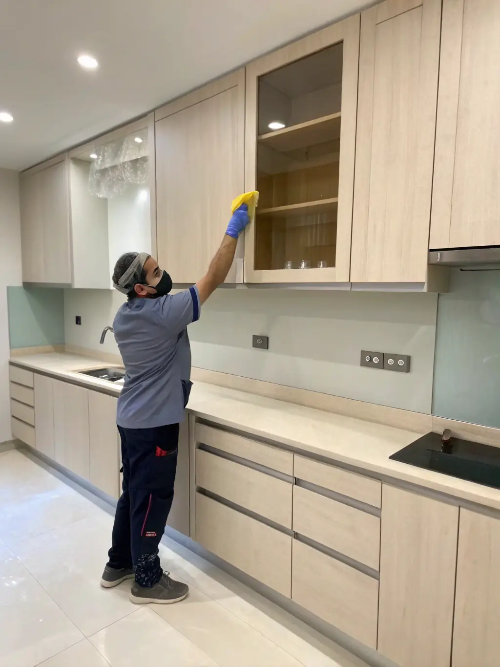 A bright, airy photo of an empty apartment being cleaned after tenants have moved out, with workers wiping down walls and sanitizing surfaces, representing pre/post-move cleaning.